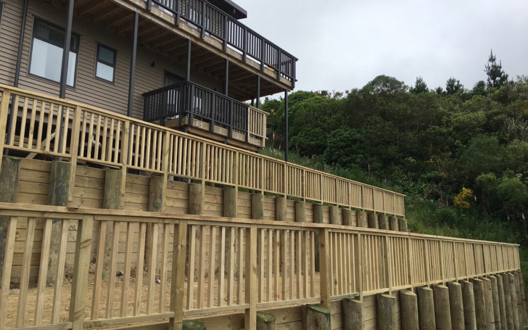 Multi-level timber retaining walls and fences on a sloped property, showcasing robust outdoor solutions.